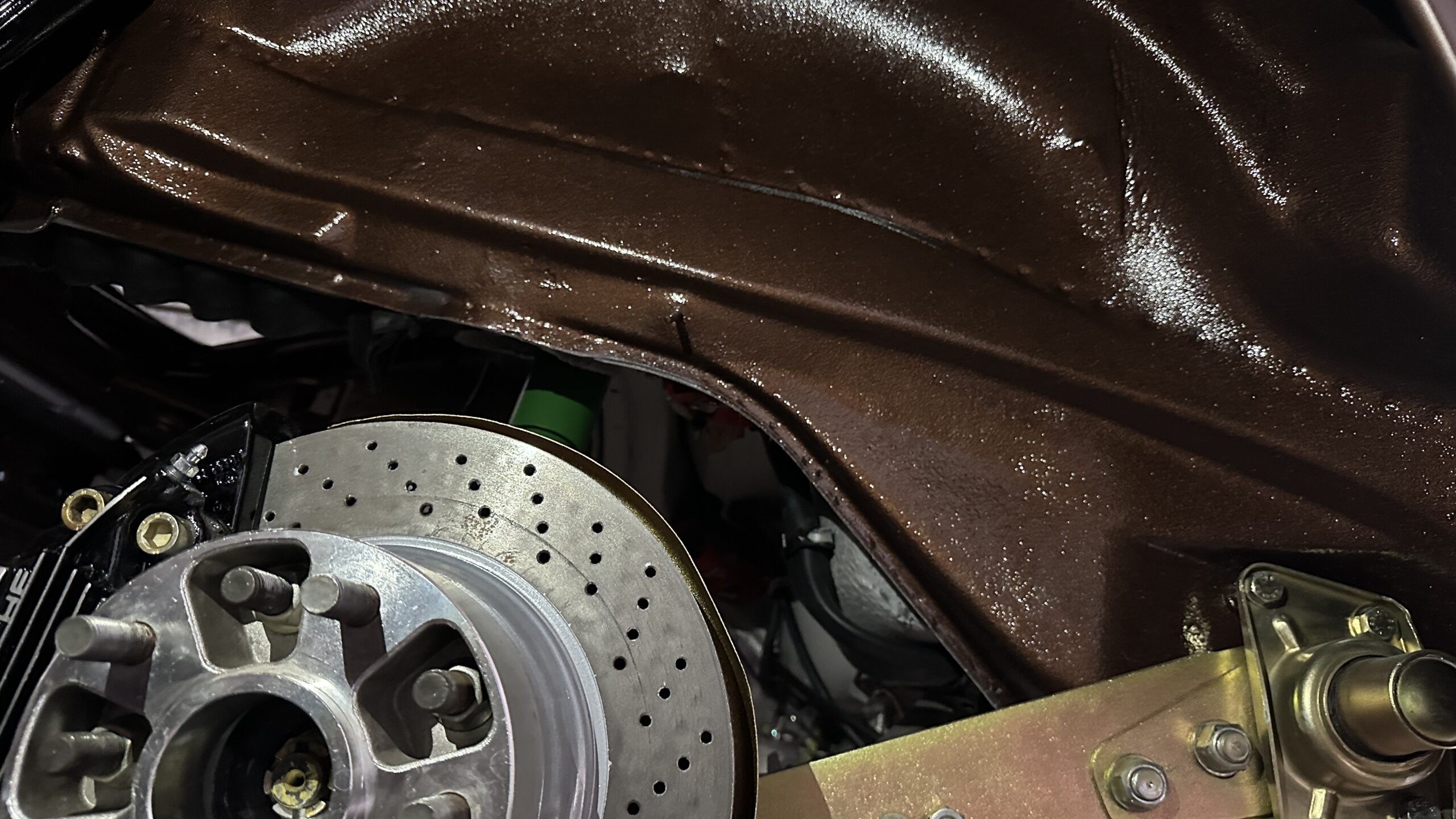 we can see the right rear brake fully installed, and the lower fender has been treated with 3M waterproofing bed liner to protect the metal and restore its classic corrugated paint texture under the car.